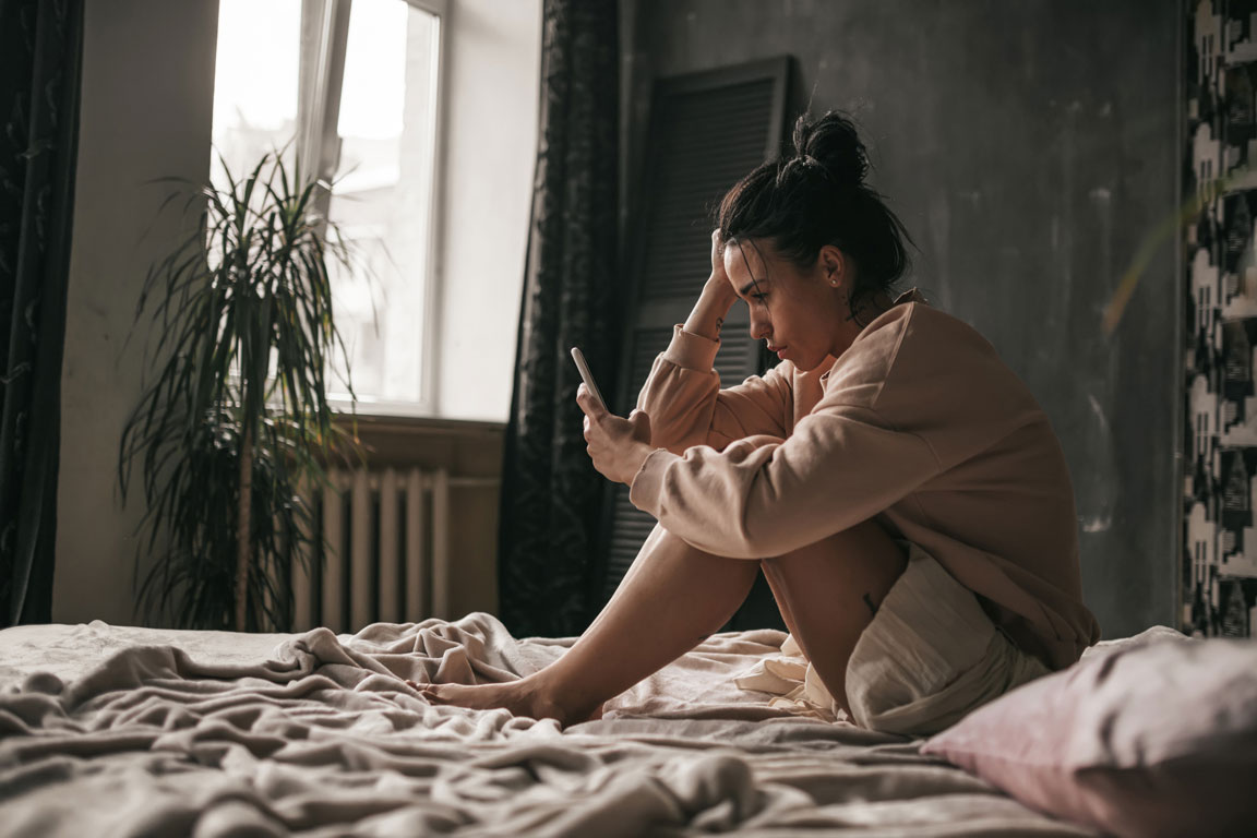 young adult woman getting anxiety looking at her cell phone
