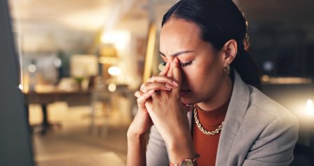 Women with folded hands and eyes closed looking troubled