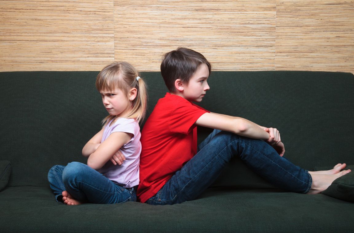 angry siblings sitting with their backs turned to each other