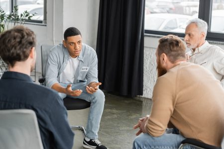 African american man with alcohol addiction sharing problem during group therapy session in rehab center Addiction Counseling